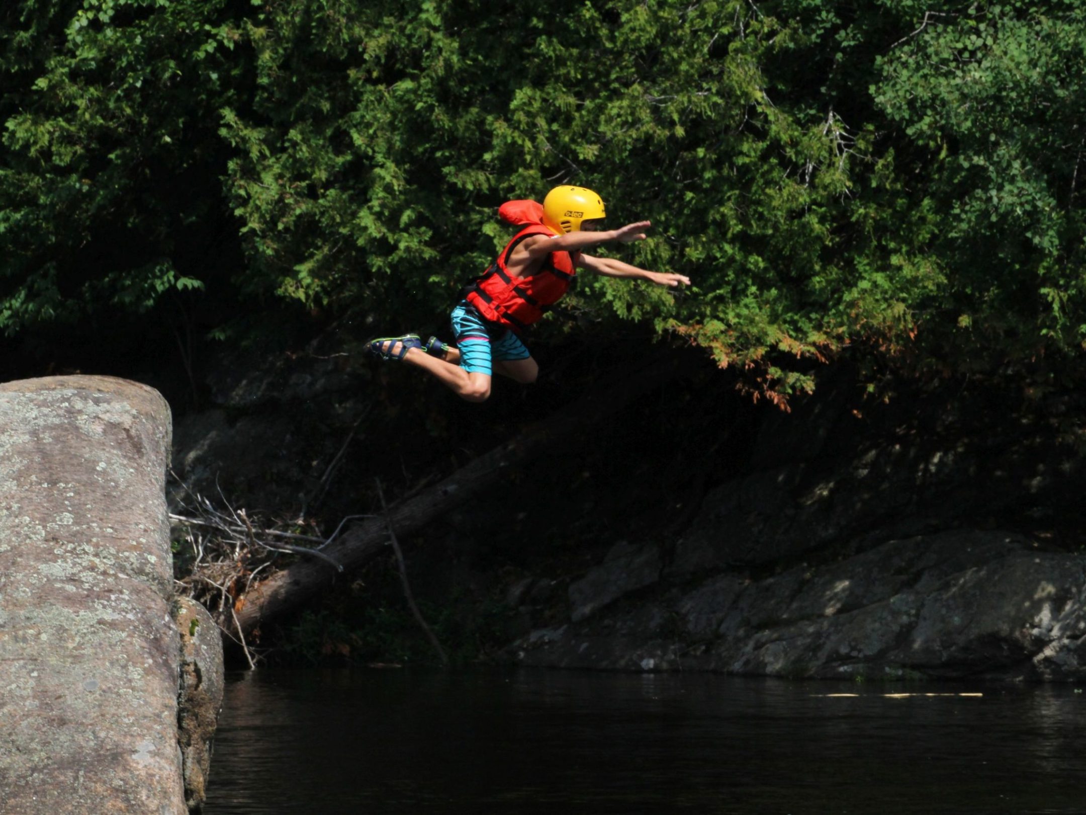 a man flying through the air while riding a snowboard down a river